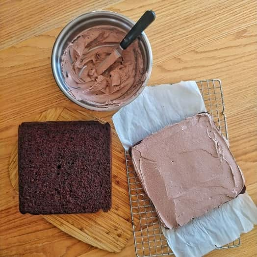 Partially frosted chocolate cake on the table.