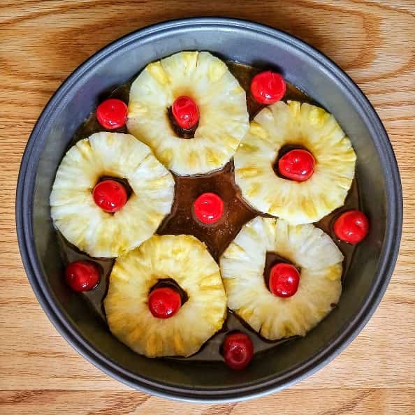 Cake pan with Pineapple rings arranged with Maraschino cherries.