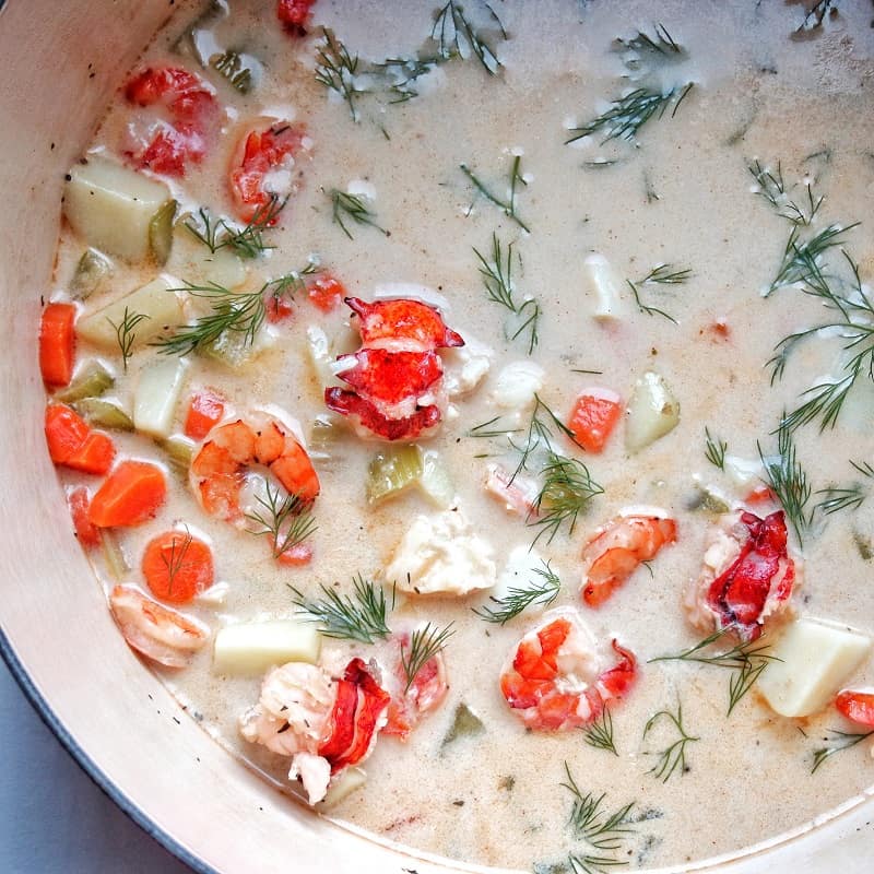 Dairy free seafood chowder in a pot with fresh Dill garnishing.
