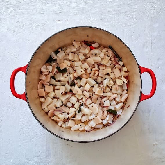 Squid curry ready for preparation in a red Le creuset cast iron pan.