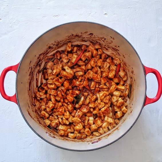 Squid curry in  preparation in a red Le creuset cast iron pan.